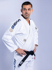 A man stands confidently with his hands on his hips, wearing the SEKAI 3.0 BJJ Gi White Navy and a black belt, looking to the side against a plain light background.