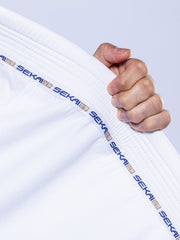 A hand grips the collar of the SEKAI 3.0 BJJ Gi White Navy, featuring "SEKAI" repeated in blue along the trim. The background is plain and light-colored.