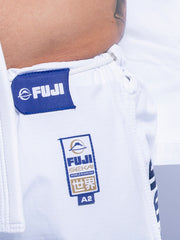 Close-up of a person wearing the SEKAI 3.0 BJJ Gi White Navy pants with a blue Fuji patch and FUJI SEKAI WORLD RANKING label featuring Japanese characters; part of a bare torso and gi jacket is also visible.